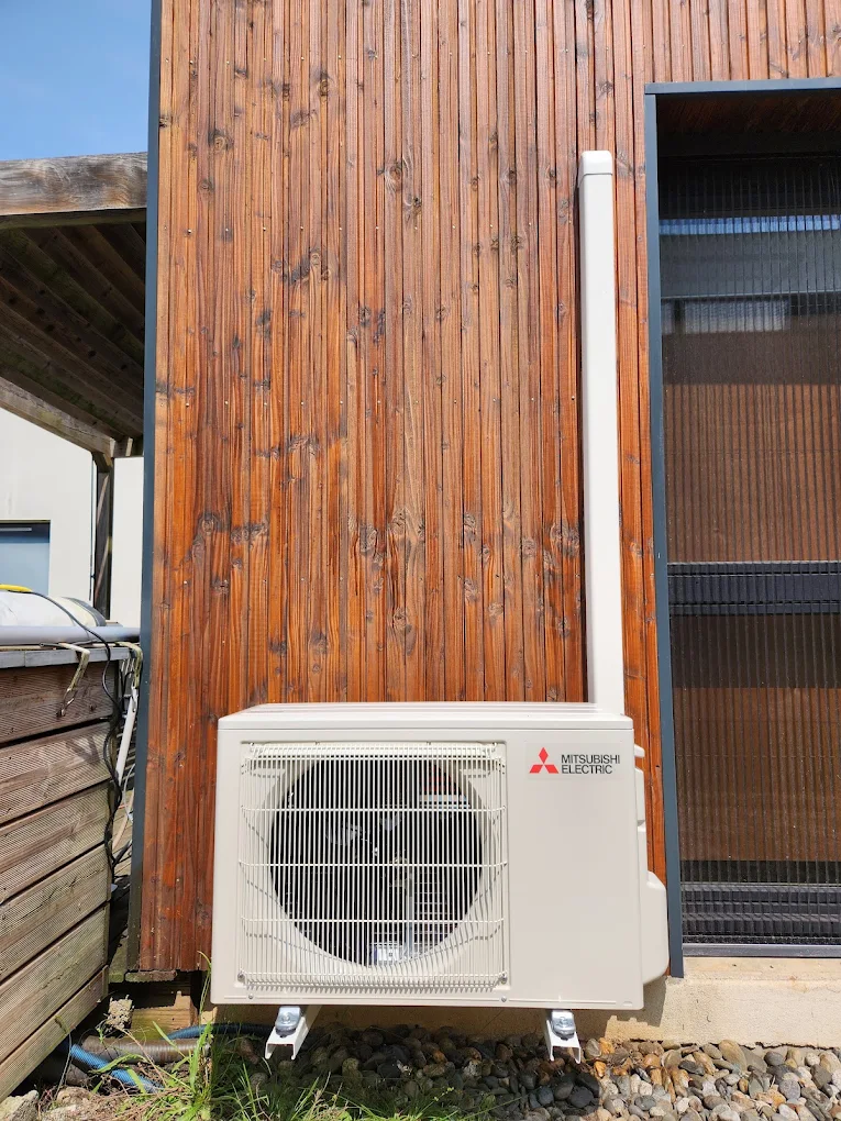 Groupe extérieur Mitsubishi Electric devant une façade en bois